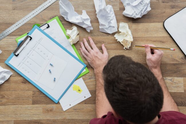 image de quelqu'un qui travaille avec plein de feuille chiffonnées
